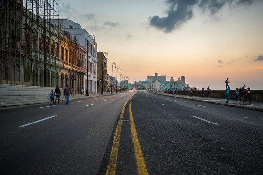 Antique cars and people strolling on the malecon in Havana, Cuba