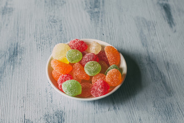 Close up view of fruity jelly candies on a bowl on wooden background.  