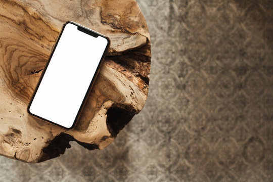 Blank screen smartphone with empty copy space mockup on solid wooden stool and carpet. Flat lay, top view template for social media, website, magazine.