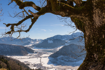 Blick ins Tal im Winter eingerahmt von knorrigen Ast