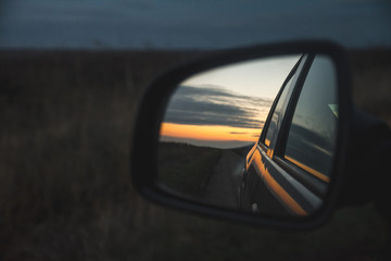 Colors of sunset in the rear view mirror of a car