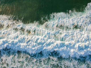 aerial view from a big wave crashing in a beach. Drone view