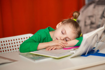 Fototapeta na wymiar little cute girl of 7 years old, first grader, left-hander does homework at the table, homework and fell asleep at her desk on notebooks