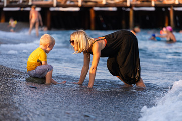 Mother and son having fun on the beach at sunset
