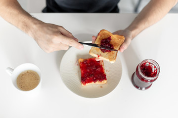Top view spreads cherry jam on toast
