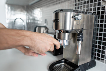 Guy prepare delicious aromatic coffee in a coffee machine. A simple way to make coffee