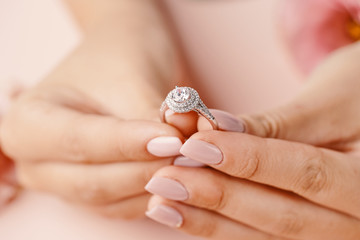 Close up of woman's hand holding elegant diamond ring.