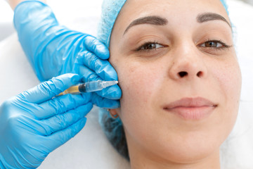 Close-up, beautician makes beauty injections into the skin of a young beautiful girl. Facial care and rejuvenation.