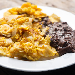 Mexican scrambled eggs with corn tortilla also called migas on wooden background