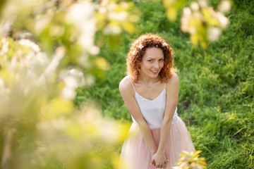 Fototapeta na wymiar Young attractive girl walks in spring green park enjoying flowering nature