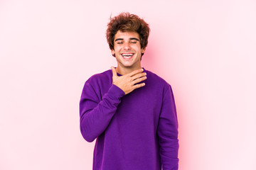Young caucasian man against a pink background isolated laughs out loudly keeping hand on chest.