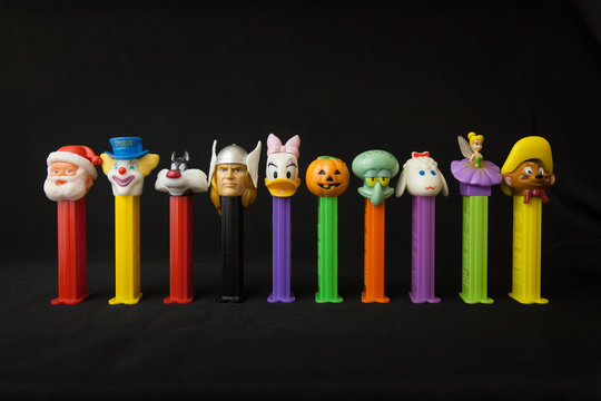 WOODBRIDGE, NEW JERSEY / UNITED STATES - January 16, 2020: A variety of Pez dispensers are lined up on a black background