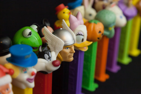WOODBRIDGE, NEW JERSEY / UNITED STATES - January 16, 2020: A variety of Pez dispensers are lined up on a black background