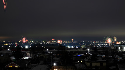 Night cityscape with lots of exploding holiday fireworks.