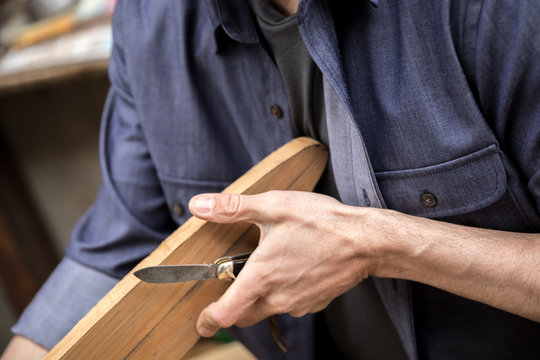 A man carving an oar with a knife