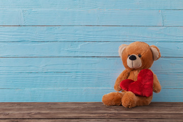 Teddy bear with red heart on old wooden background. Valentine's