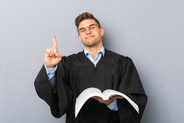 Young jurist holding a book showing number one with finger.