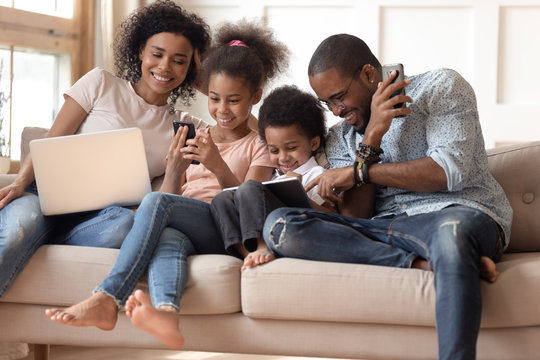 Happy addicted to gadgets black family using different devices.