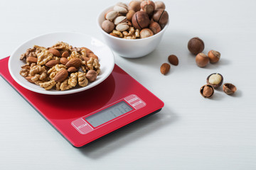mix of different nuts on  kitchen scale on a white table
