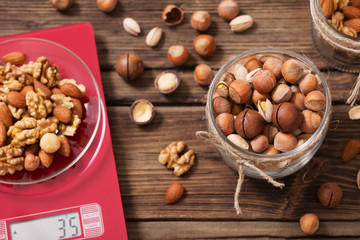 mix of different nuts on  kitchen scale on old wooden background