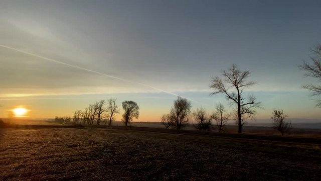 Panoramic view of winter sunrise in field without snow.