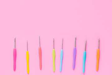 Various size bright crochet hooks on pink background