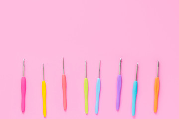 Various size bright crochet hooks on pink background