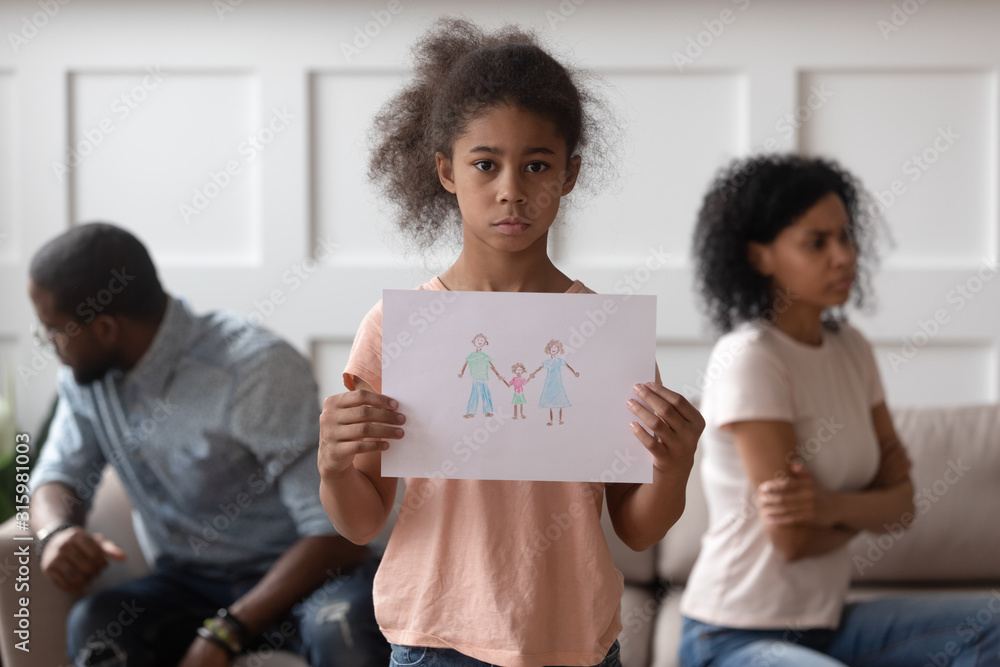 Wall mural stressed small girl holding picture with happy family.