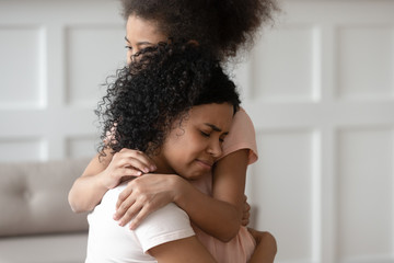 Obraz premium Close up sad upset black woman cuddling daughter.