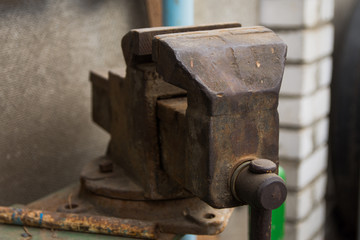 An old rusty vise, located in the inner yard of the old village house. Workshop concept. Tools and hardware for everyday. Construction and repair. Selective focus