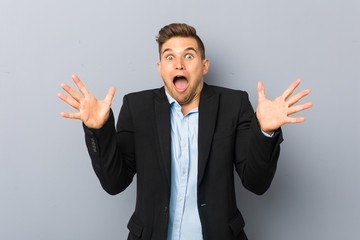Young handsome caucasian man celebrating a victory or success, he is surprised and shocked.