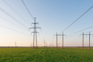 Electrical net of poles on a panorama of blue sky and green meadow