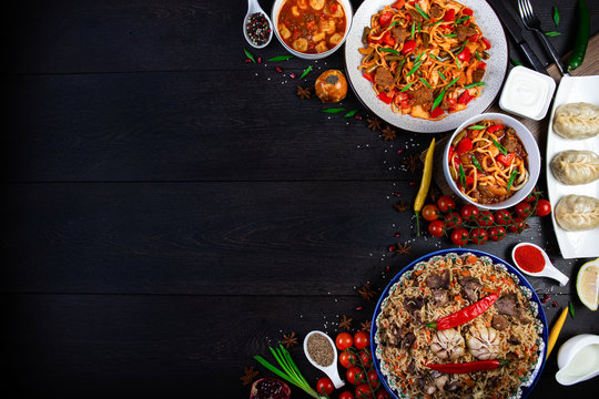 The concept of oriental cuisine. Assorted Uzbek food set, pilaf, samsa, lagman, manta, shurpa Uzbek restaurant concept, Uzbek food. Homemade Uzbek pilaf or plov from lamb served in cast iron cookware