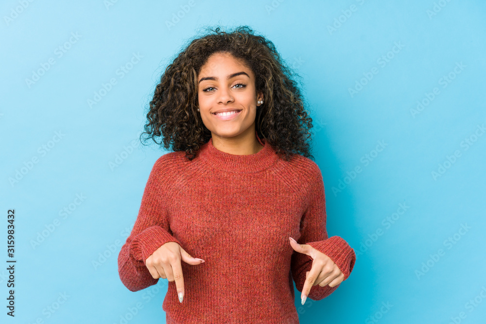Wall mural young african american curly hair woman points down with fingers, positive feeling. - Wall murals