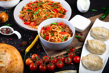 The concept of oriental cuisine. Assorted Uzbek food set, pilaf, samsa, lagman, manta, shurpa Uzbek restaurant concept, Uzbek food. Homemade Uzbek pilaf or plov from lamb served in cast iron cookware