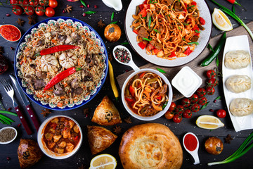 The concept of oriental cuisine. Assorted Uzbek food set, pilaf, samsa, lagman, manta, shurpa Uzbek restaurant concept, Uzbek food. Homemade Uzbek pilaf or plov from lamb served in cast iron cookware