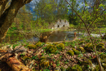 An ancient water mill, its ruins stand by the river.