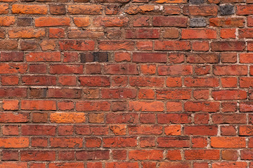 Old brick wall. Wall of a medieval church made of red weathered brick. Background and texture.
