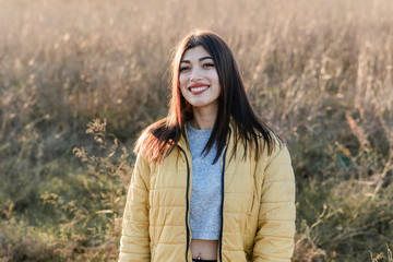 Chica joven con abrigo amarillo en un prado