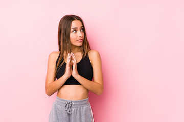 Young caucasian fitness woman posing in a pink background making up plan in mind, setting up an idea.