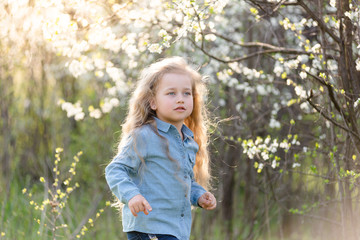 Little blonde girl having fun in the spring park.