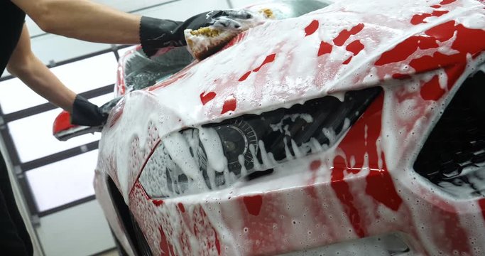 Manual wash for perfect clean car. Cleaning car using high pressure water, Man cleaning vehicle with high pressure water spray or jet. Car wash details, Close up concept. 