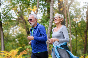 Cheerful active senior couple jogging in the park. Exercise together to stop aging.