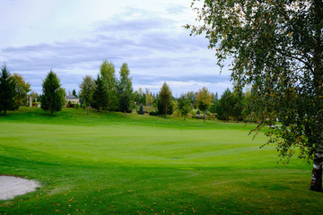 View of the golf course with green lawn trees and ornamental shrubs. Golf course, beautiful scenery.