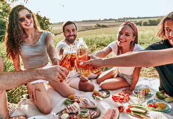 Group of happy friends having fun and drinking non-alcoholic beer or soda lemonade on park