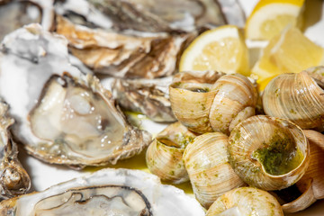 Oyster snails and slices of juicy lemon on a white plate in a Chinese restaurant.