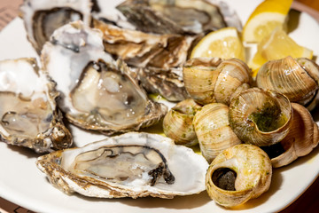 Oyster snails and slices of juicy lemon on a white plate in a Chinese restaurant.