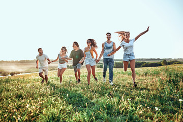 Happy group of friends celebrating and having fun on the hill. Young people on summer holiday
