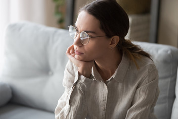 Stressed millennial woman in eyeglasses thinking over problems.