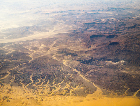 Aerial view on African stone desert with sand dunes and road. Mountain landscape with mountain peaks and hills as abstract background for your project presentation about geography or travels.